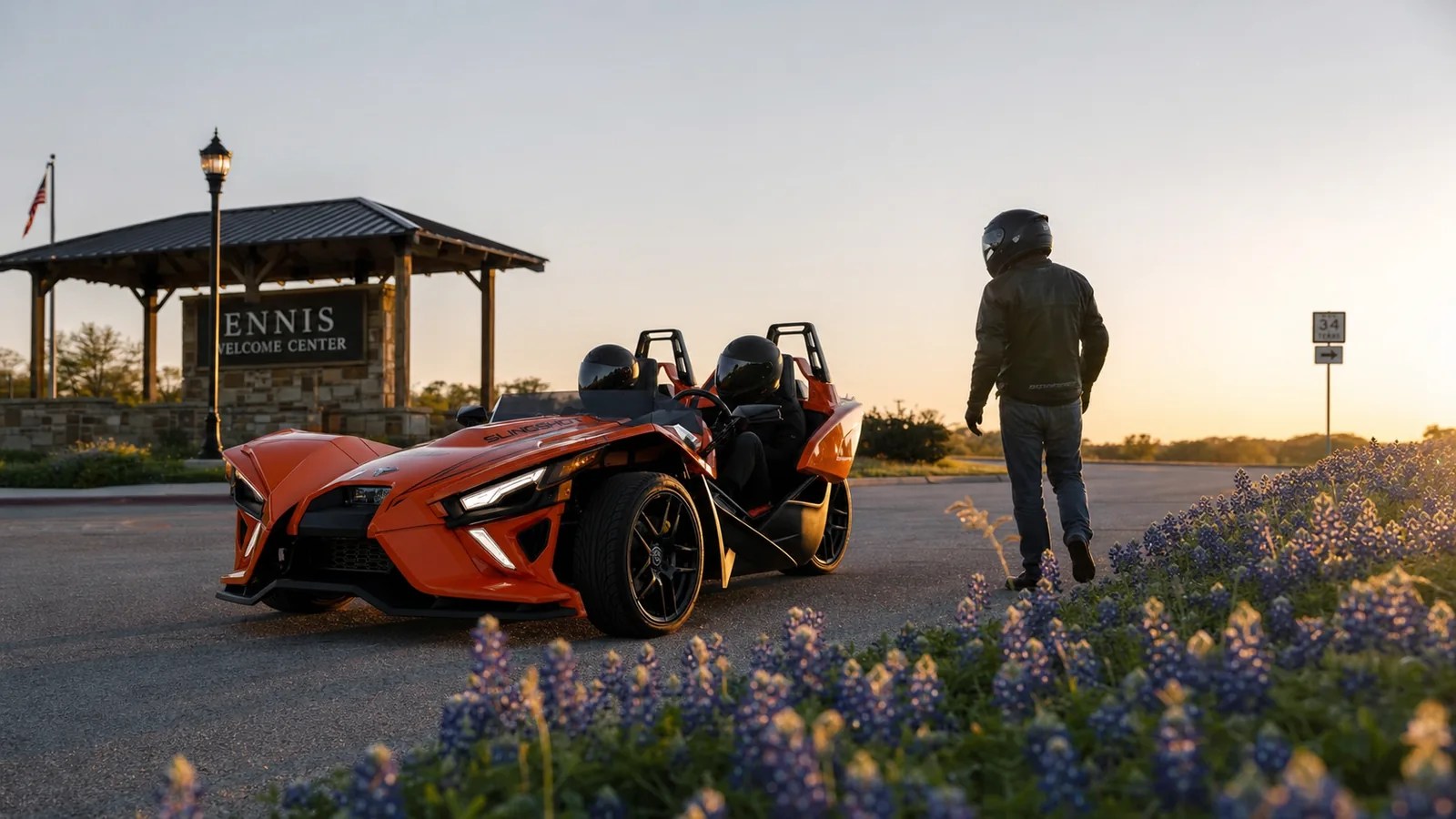 An orange Polaris Slingshot parked outside the Ennis Welcome Center at golden hour. Hero image for the Ennis Slingshot article "Your First 15 Minutes: How Our Orientation and Safety Briefing Works"
