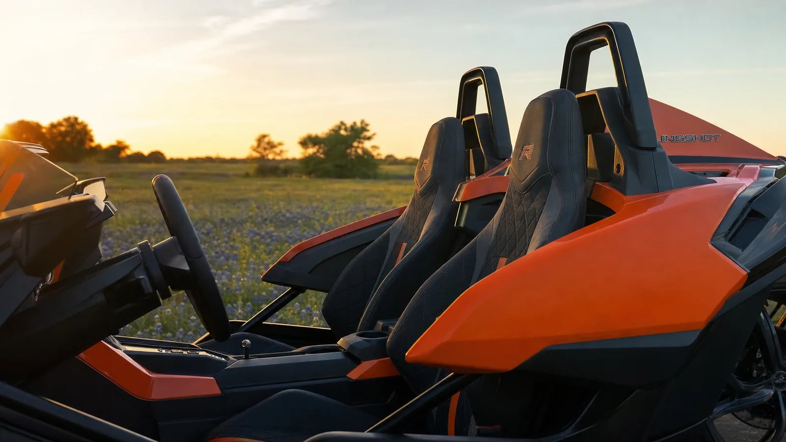 A close interior detail of the bucket seats and cockpit of an orange Polaris Slingshot at golden hour. Hero image for the Ennis Slingshot article "Is a Polaris Slingshot Comfortable? Seats, Legroom, Ride Quality and Getting In and Out"